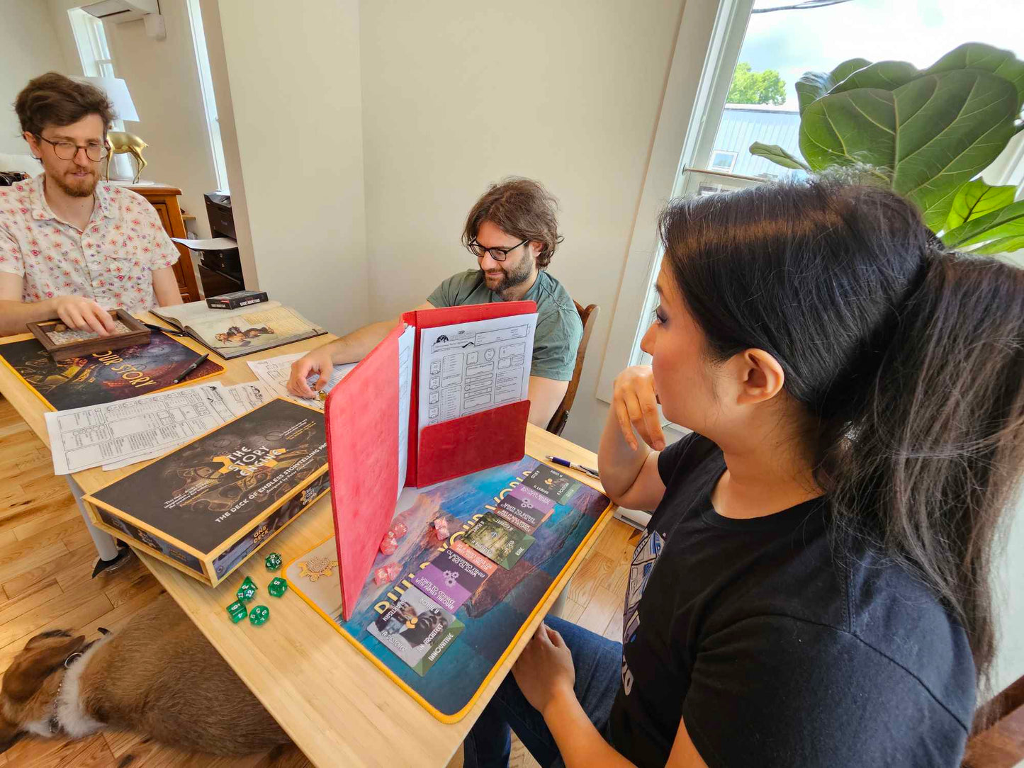 Three TTRPG players sitting at the gaming table playing D&D with The Story Engine Deck of D&D prompts with a DM screen up
